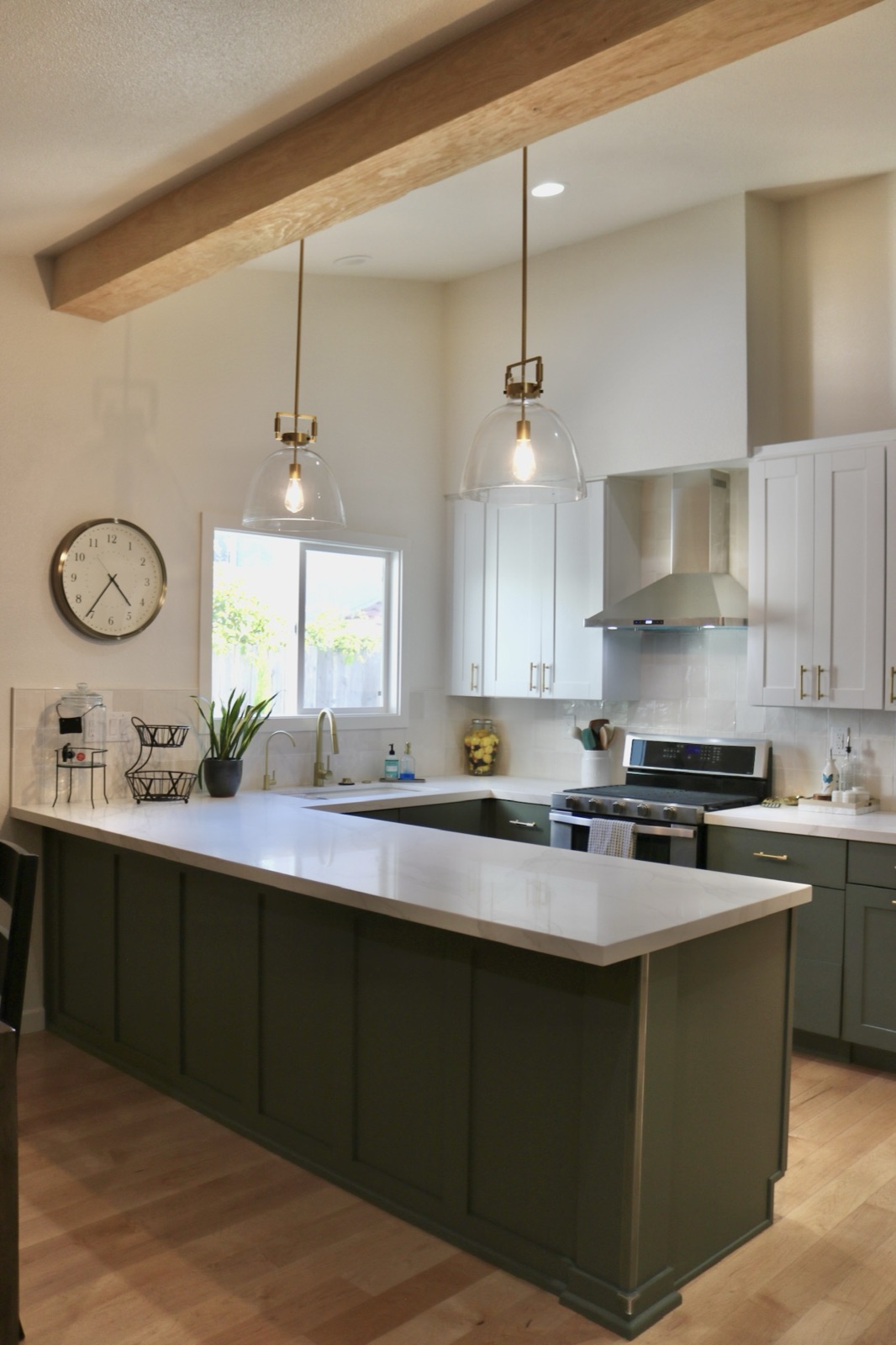 Kitchen with a green island, white cabinetry, and pendant lights